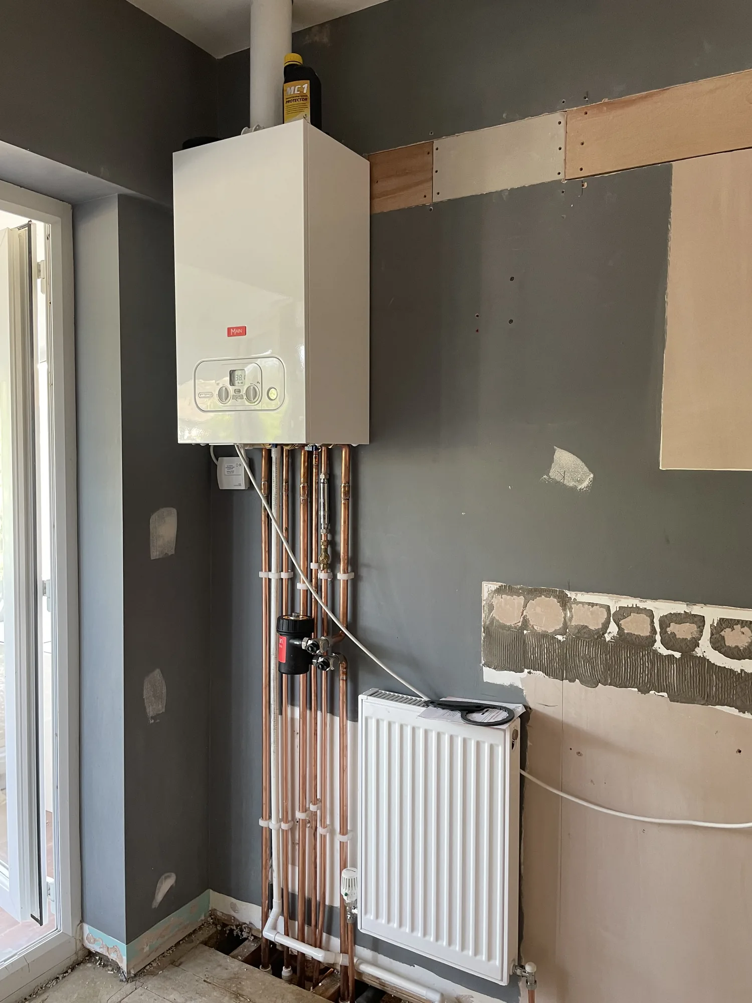 Boiler installation in progress above a radiator