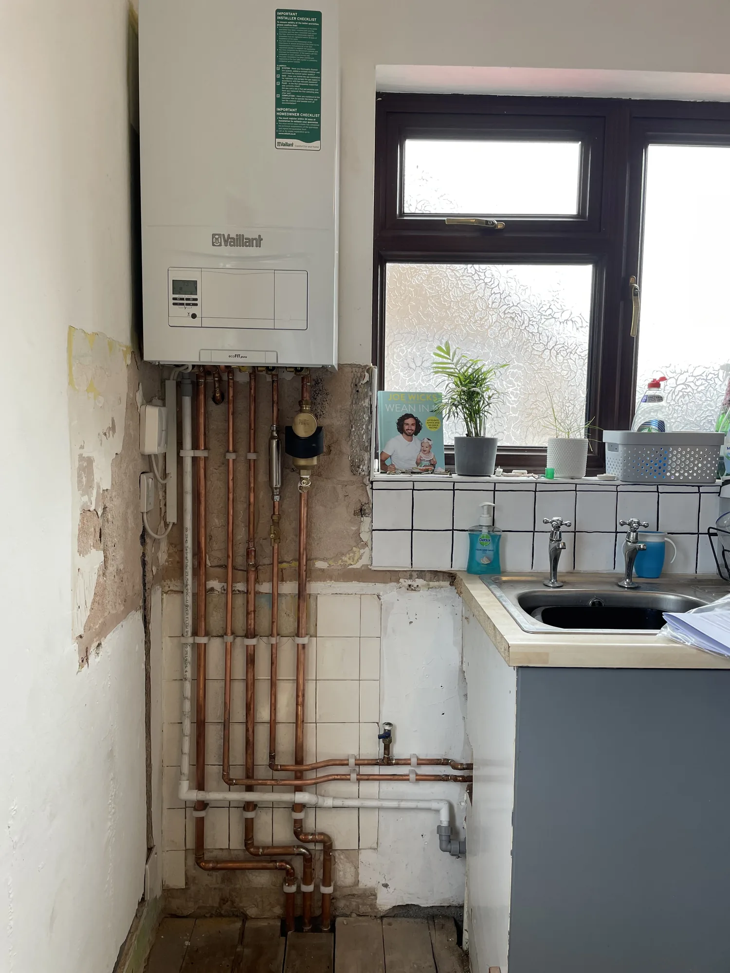 Vaillant boiler installation in progress beside a kitchen window
